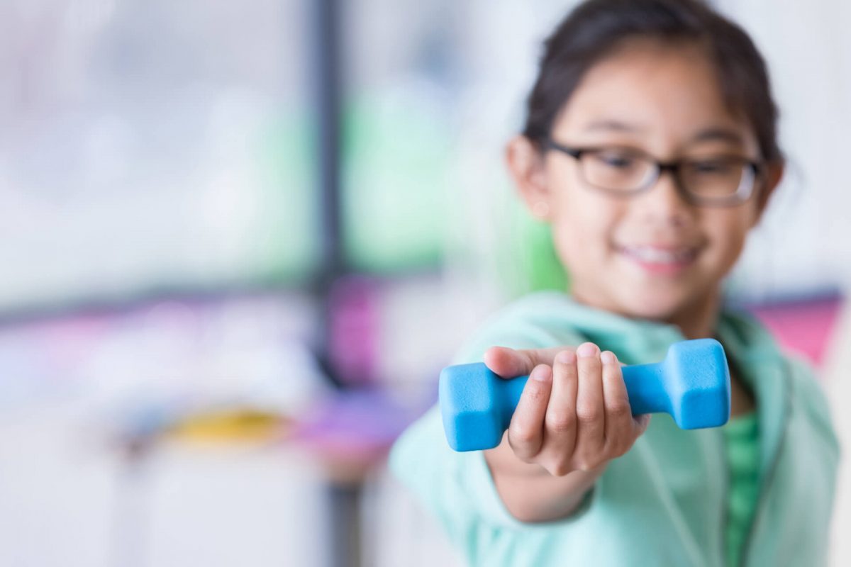 A girl holding a blue dumbbell in her hand.