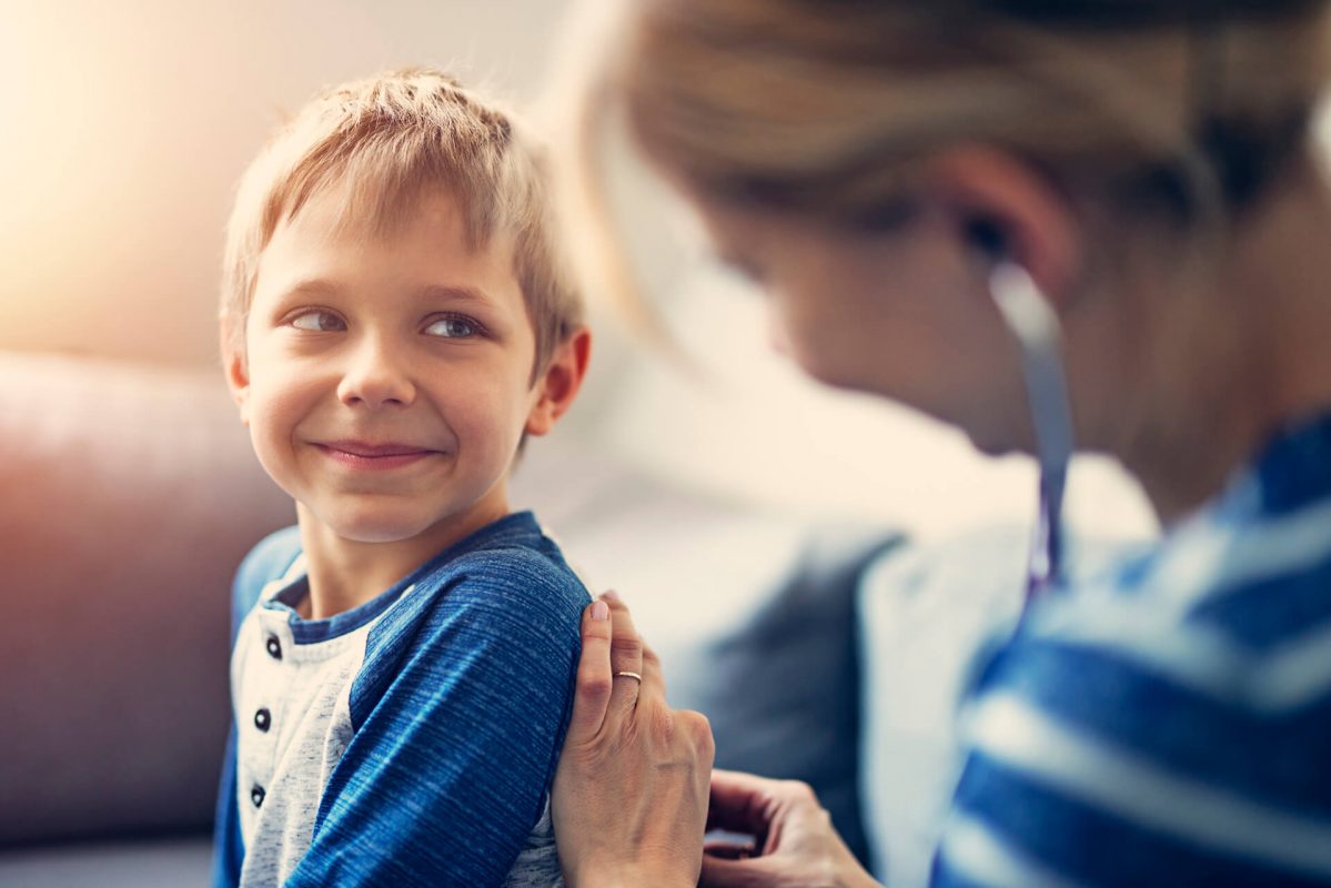 A young boy smiles while being held by an adult.