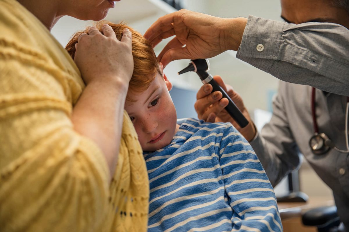 A boy getting his head shaved by two men.