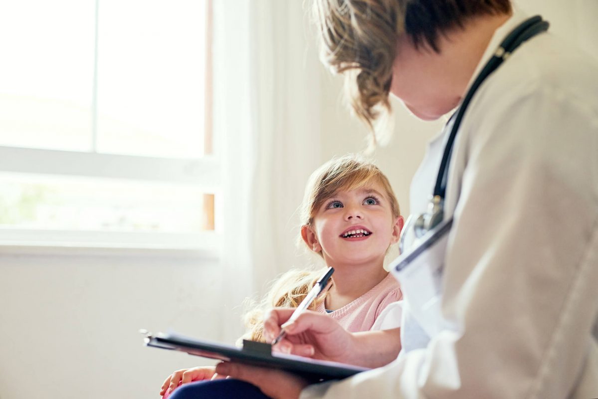 A young girl is sitting on the lap of her doctor.