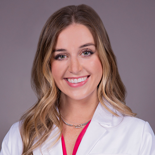 A woman in white lab coat smiling for the camera.